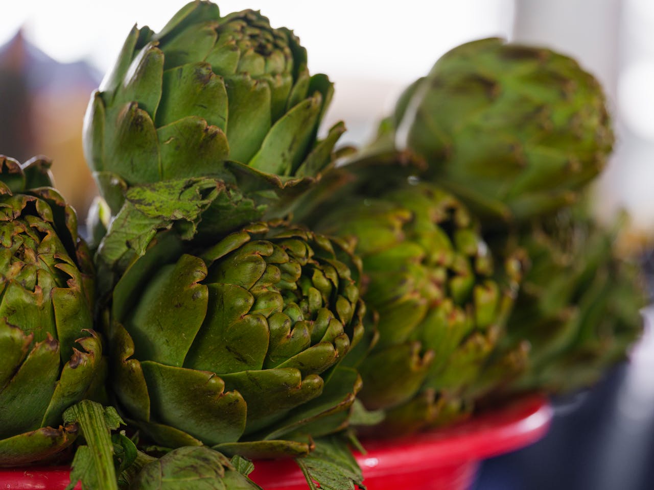 Close-up of fresh, organic artichokes on a red tray at a market stall. Vibrant and healthy.